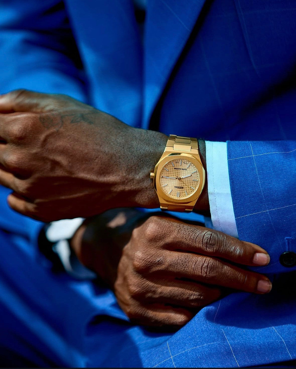Yellow gold Astral Date Master on the wrist with a blue suit