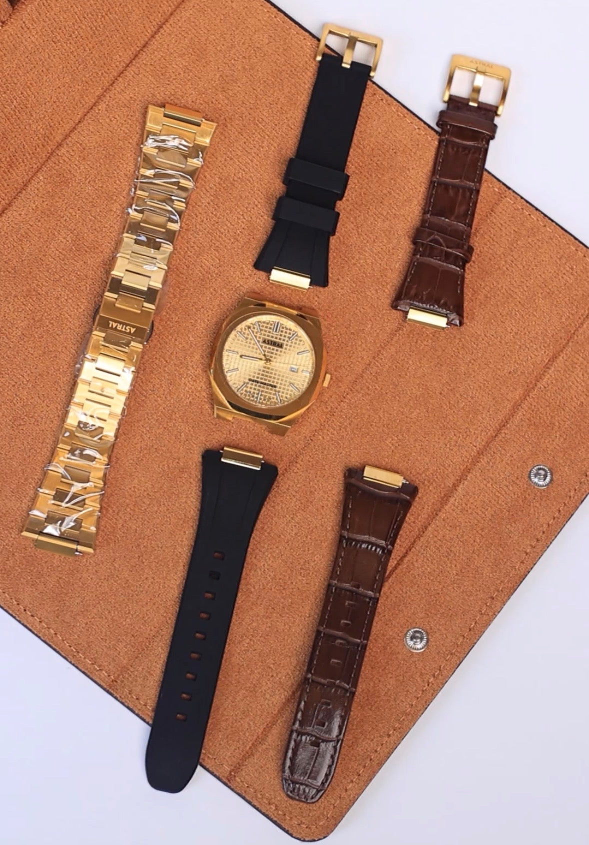 One gold Astral Date Master with a steel bracelet, two silicone and two leather straps